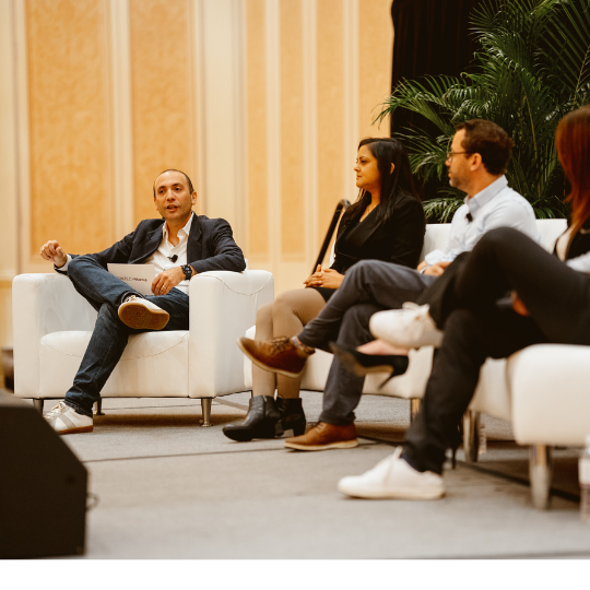 A picture of a man on stage with panelists