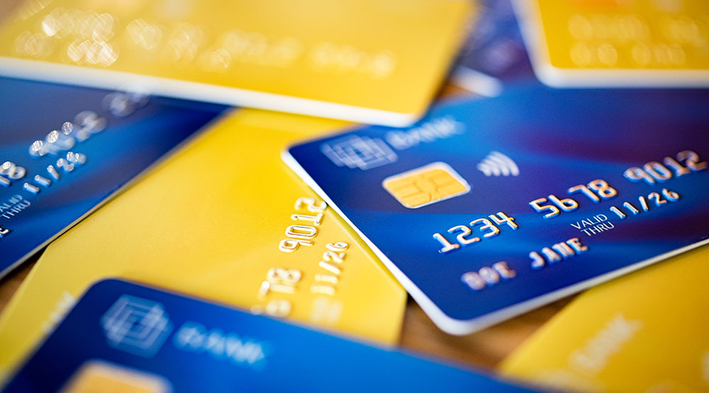 A pile of assorted bank cards in blue and yellow to illustrate the report 'Regulations and cost disclosure in cross-border card payments'